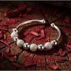 Detailaufnahme Nivia Ring auf rotem Holzuntergrund: Zeigt deutlich den Kontrast zwischen den sandgestrahlten (matten) und polierten Silber-Perlen.