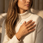 Frau im beigen Rollkragenpullover trägt eleganten goldenen Fidget Ring Aurelia als modisches Accessoire gegen Stress.