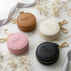 Ästhetische Schmuckaufbewahrung für die Reise: Runde Mini-Etuis aus veganem Leder auf Marmor mit Gold-Details.