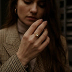 Frau trägt goldenen Anti-Stress Ring Aurelia am Mittelfinger, elegantes Outfit, VÉYNOMA Schmuck gegen Unruhe.
