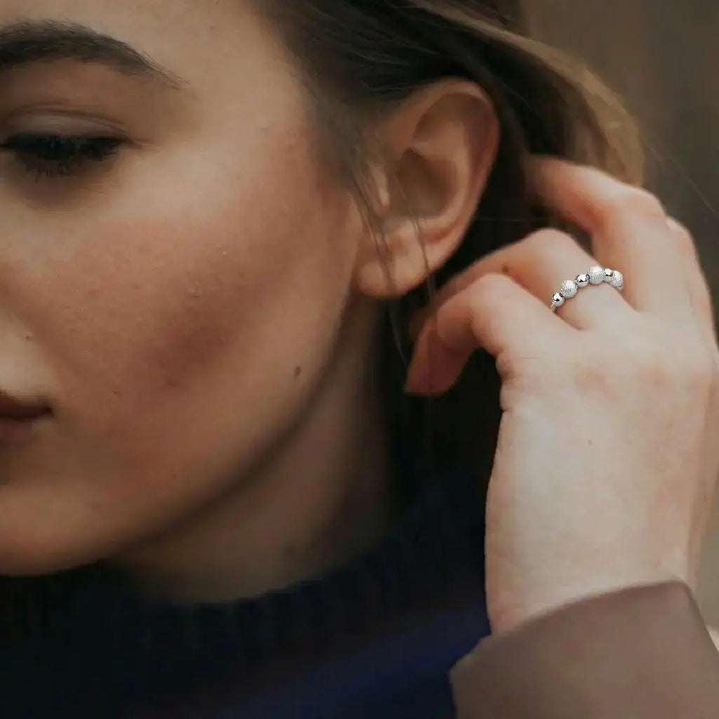 Frau trägt eleganten silbernen Perlen-Ring von VÉYNOMA. Diskreter Schmuck gegen Stress, rhodiniert und anpassbar (One Size).