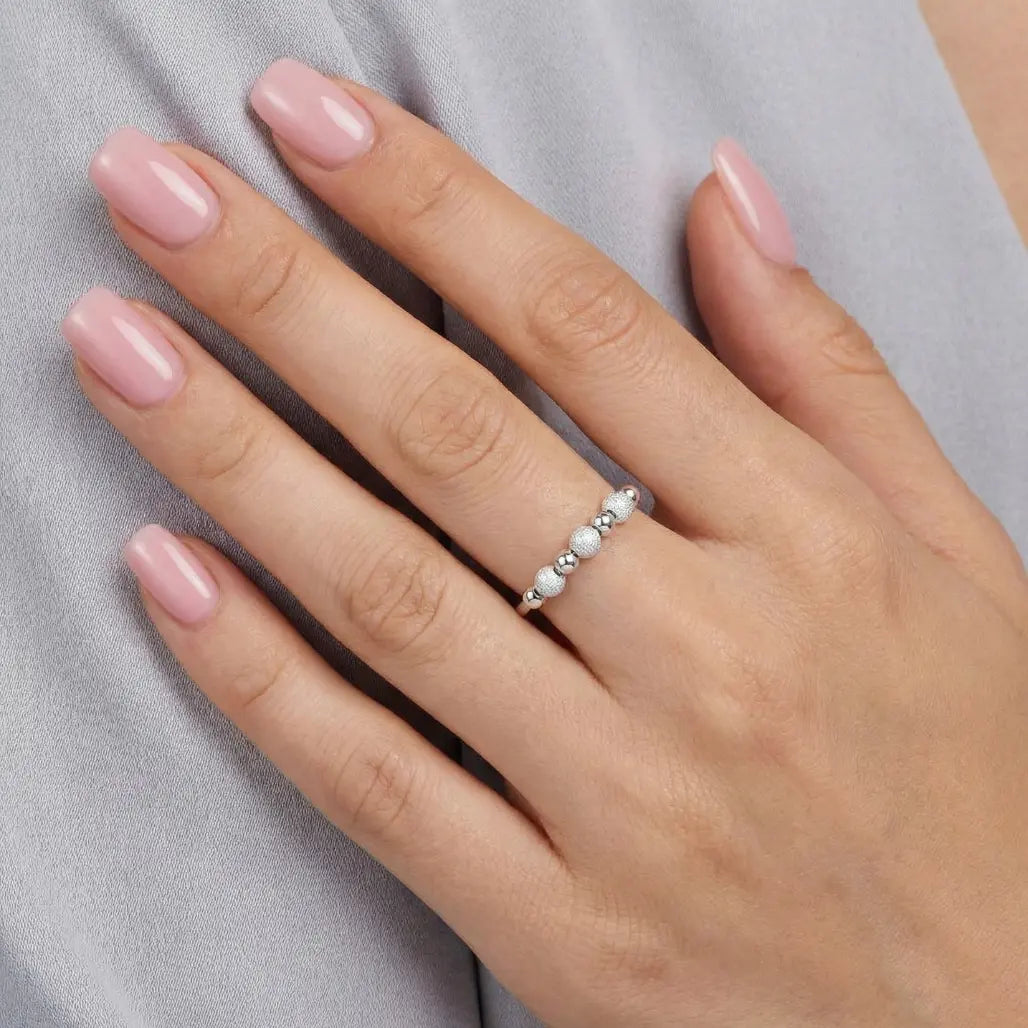 Hand trägt VÉYNOMA Nivia Anti-Stress Ring aus 925er Silber. Größenverstellbarer Fidget-Ring mit beweglichen Perlen zur Beruhigung bei Nervosität.